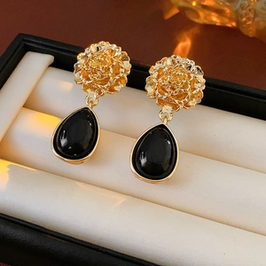 Detail of vintage flower stud earrings with black teardrop pendants in a jewelry box