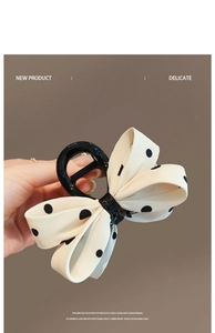 Gros plan sur une pince à cheveux avec un nœud en tissu à pois beige et noir