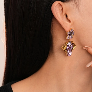Close-up of vintage flower earrings with purple teardrop crystals worn by a model