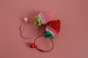 Close-up of handmade crochet strawberry charms with green leaves and matching bells