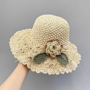 Handmade straw sun hat for women with crochet flowers and beige woven texture