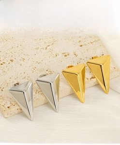 Macro shot of 3D geometric triangle stud earrings in polished gold and silver finishes