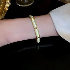 Detailed close-up of gold-plated cat's eye stone bracelet with geometric bamboo link design