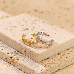 Macro detail of gold and silver leaf-shaped ear cuffs with sparkling stones on stone base