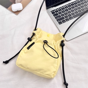 Dettaglio borsa a tracolla gialla in nylon con coulisse e accessori da ufficio