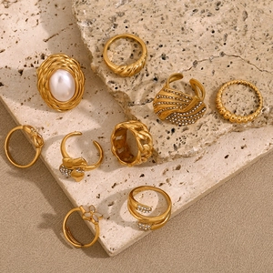 Set of eight 18K gold plated rings with pearls and crystals on beige travertine