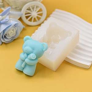 Detail of a 3D bear silicone mold with a finished blue flower bear candle on a yellow background