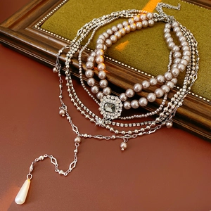 Detail of layered pearl and silver chain necklace with a vintage square crystal pendant