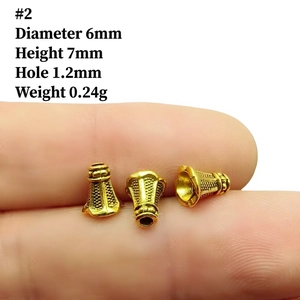 Macro shot of a 6mm golden alloy flower spacer bead for DIY jewelry on a fingertip