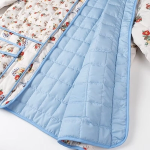 Close-up of quilted floral fabric with contrast blue piping and button detail