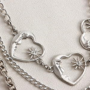 Close-up of silver metal chain with celestial moon and sun face heart pendants
