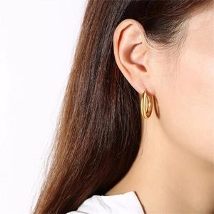 Side view of model wearing polished gold minimalist stainless steel hoop earrings