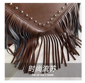 Gros plan sur le sac en cuir marron foncé avec des clous argentés et de longues franges