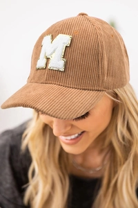 Detail of corduroy baseball cap featuring white towel-embroidered letter M patch