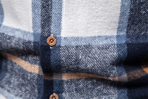 Detailed macro view of blue and white plaid shirt fabric with engraved fashion button