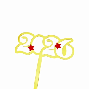 Close-up of golden 2026 acrylic cake topper with red stars for New Year party decor