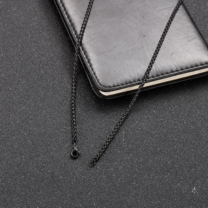 Close-up of black wheat chain necklace with lobster clasp on leather background