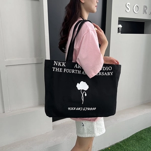 Large capacity black canvas tote bag with floral print worn by a model in casual style