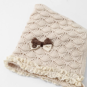 Beige knit baby hat with wave pattern, lace trim and bow accent for winter warmth