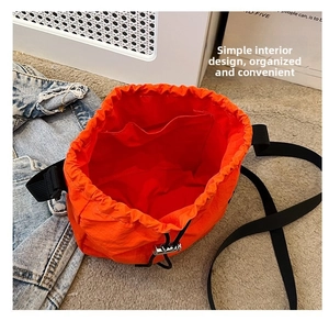 Detail view of the drawstring bucket bag interior with orange lining and pocket