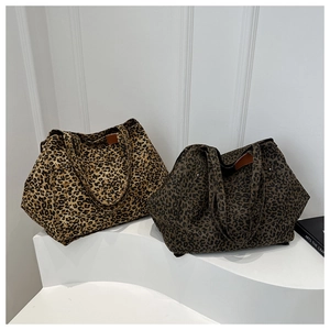 Detail view of large leopard print tote bags in two colors on a modern display stand