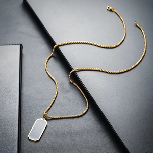 Close-up of a gold snake chain necklace featuring a minimalist black rectangular pendant