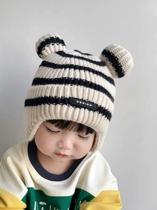 Detail of baby knit earflap hat with black and white stripes and cute bear ears