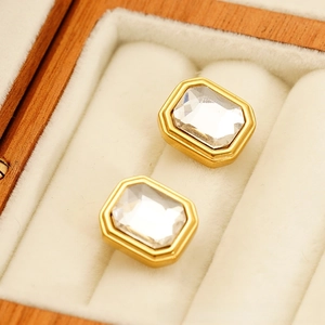 Detail view of rectangular crystal stud earrings in golden base inside a gift box