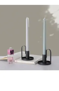 Close-up of black matte iron candle holder with a curved handle on an open book