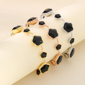Trois bracelets en acier titane avec trèfles noirs à cinq feuilles sur un présentoir