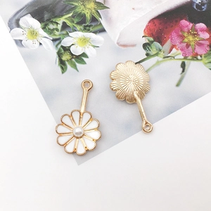 Detailed macro view of white enamel daisy pendants with pearl centers and gold base plating