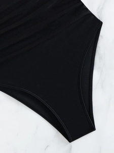 Detail shot of black one-piece swimsuit featuring reinforced stitching and elastic fabric