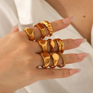 Close-up of a diverse gold ring set including signet and textured bands on fingers