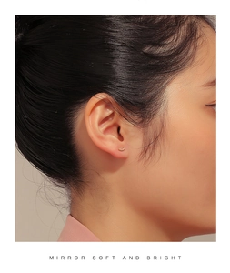 Close-up of minimalist gold curved ear stud with micro-pave cubic zirconia on ear lobe