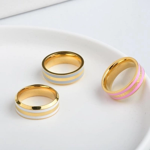 Three-piece stainless steel gold rings set with colorful enamel stripes on a tray
