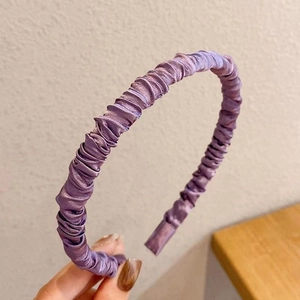 Detailed view of elegant purple satin headband featuring stylish ruched fabric texture
