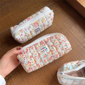 Detail of quilted cotton makeup bag with floral print showing internal storage capacity
