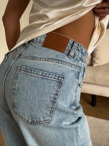 Détail de jean avec coutures sur la poche arrière et écusson en cuir à la taille