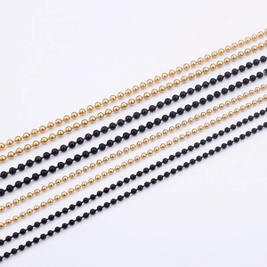 Detail of gold and black stainless steel ball chains showing metallic texture and finish