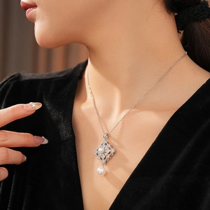 Close-up of pearl necklace featuring a diamond-set geometric flower pendant on a model