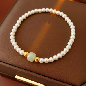 Detail of elegant pearl bracelet with green jade bead on brown leather jewelry box