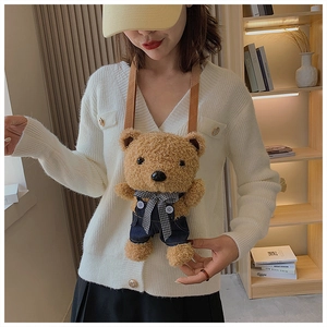 Detail of cute teddy bear plush crossbody bag featuring blue denim overalls and bowtie