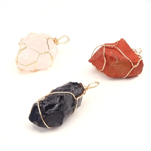 Macro shot of assorted natural crystal stone pendants wrapped in golden wire on white background