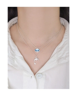 Detailed view of layered S925 silver necklace with blue gemstone and dolphin charms on a model