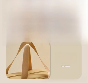 Detail view of smooth alloy zipper and widened comfortable handle on beige toiletry bag