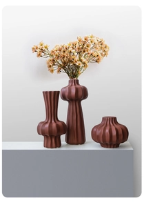 Close-up of red-brown ceramic vases featuring vertical striped textures and modern design