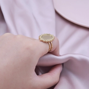 Close-up of golden geometric sunburst ring with double-band design on pink silk