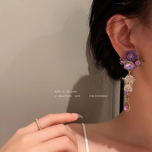Purple crystal floral drop earrings for women with gold tone accents on model