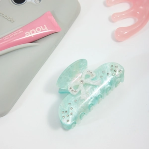Detail of mint green acetate hair claw clip with white bow and sparkling crystals
