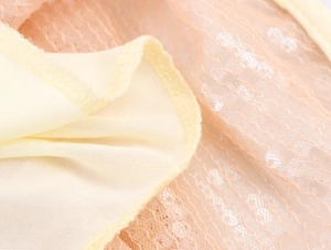 Detail of sequin party dress showing yellow knit fabric and orange lace mesh layers
